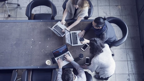 Business people in office meeting using laptops