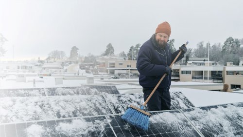 man shoveling off snow from solar panels